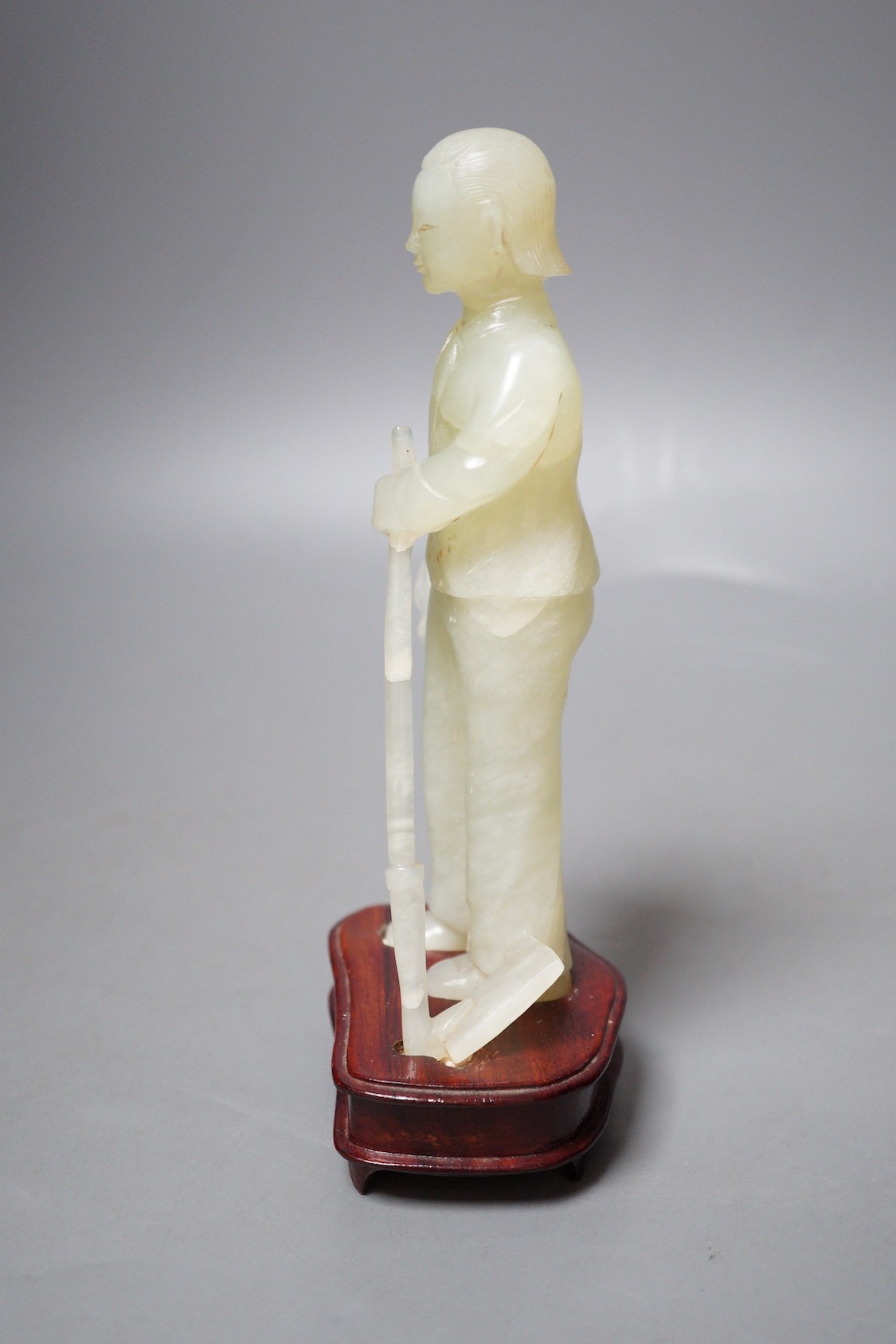 A Chinese carved bowenite jade figure of a worker on hardwood stand, 19cm